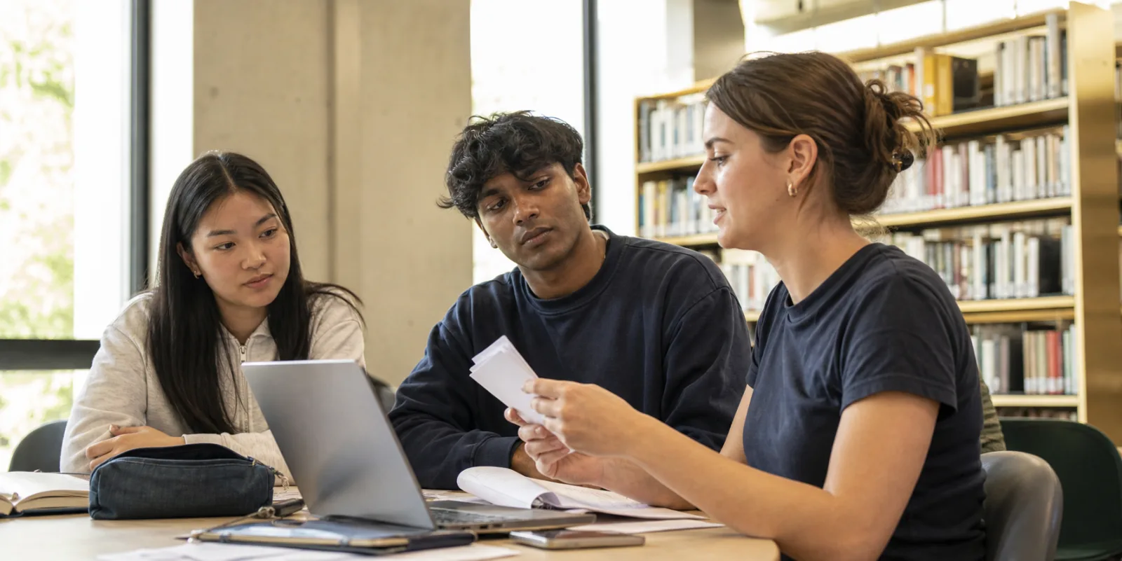 Three university students preparing a presentation with palm cards